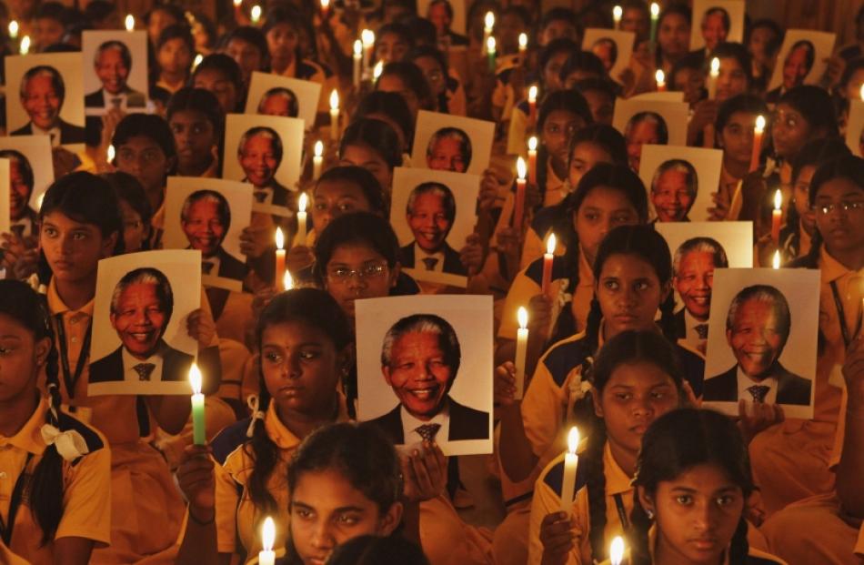 Schoolchildren hold candles and portraits of former South African President Nelson Mandela during...