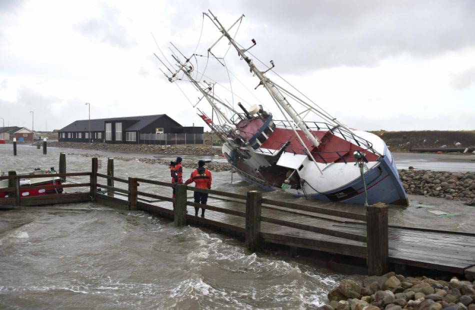 Men stand next to a stranded fishing vessel near Thorsminde Harbour December 6, 2013 as storm hit...