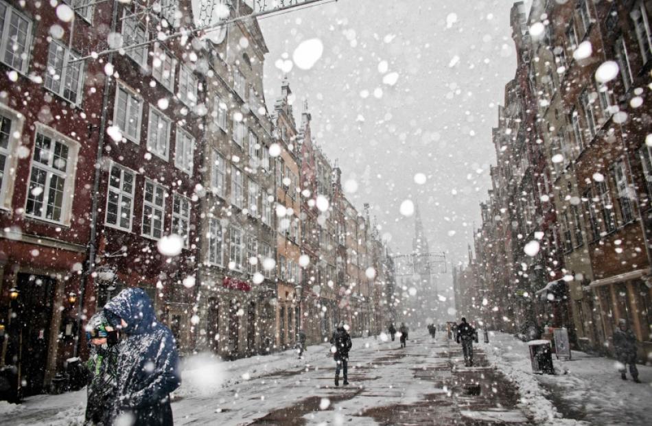 People walk during snowfalls caused by hurricane-force Xaver at Old Town in Gdansk, northern...