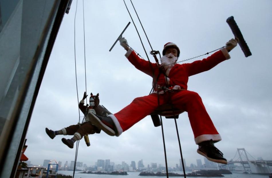 Window cleaners pose for photographers during an event to celebrate Christmas at a shopping mall...