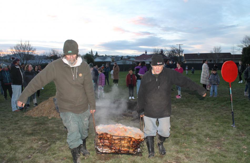 Paul Kaahu and Rodney Trainor carry food from the hāngī pit to prepare it to eat. PHOTOS: BEN...