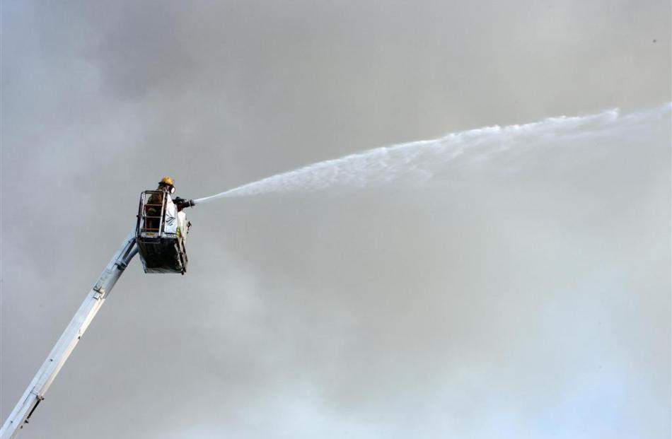 Fire fighters try to control the fires that still blaze the morning after the massive fire at...