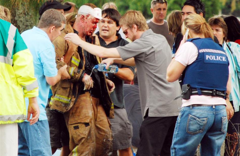 An injured fireman is assisted by people from a school gala. Photo by NZPA Phillipa Stevenson.
