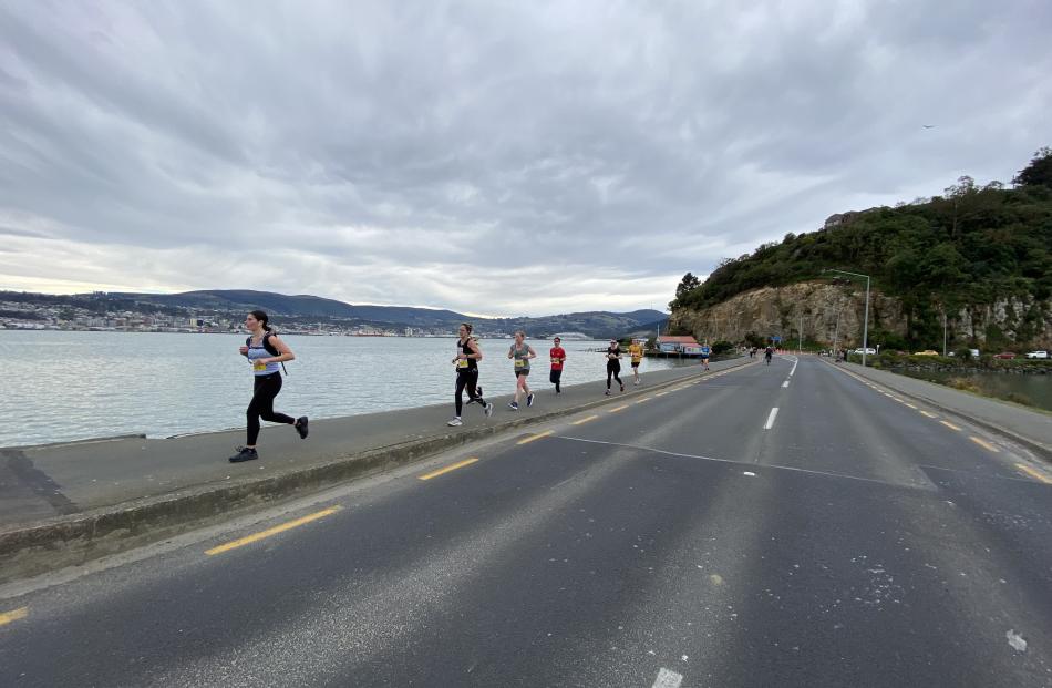A dramatic sky and the harbour surround runners on the Andersons Bay causeway.