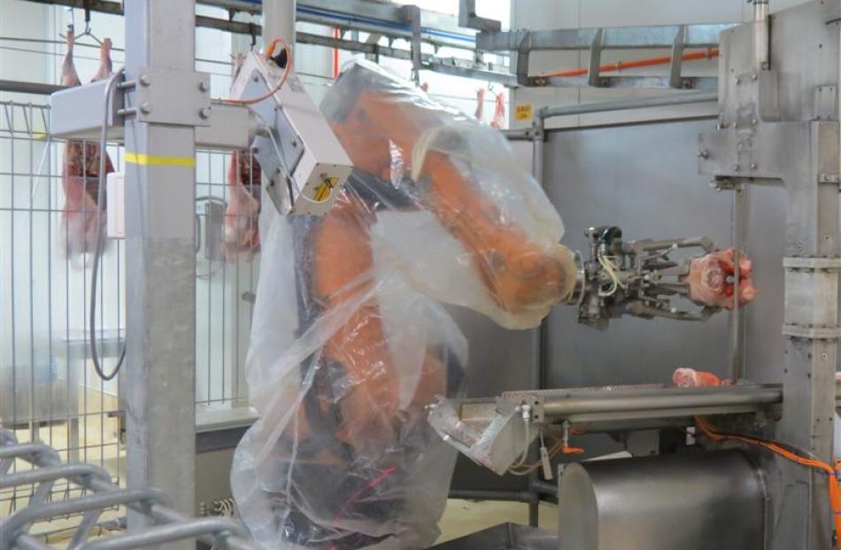 A robotic arm puts a meat cut through a bandsaw at the Finegand freezing works near Balclutha.