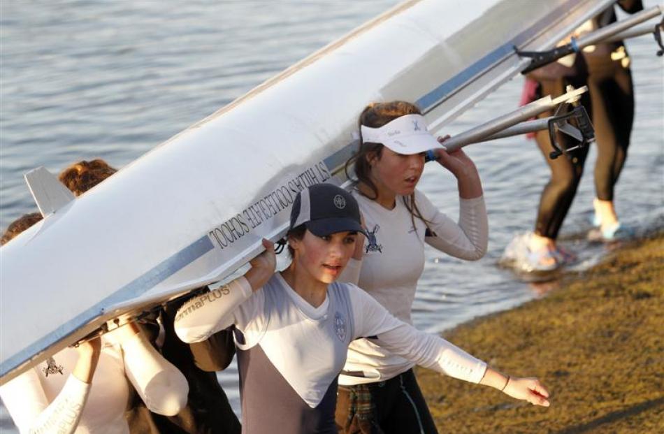 St Hilda's rowers Lili Sabonadiere (left) and Stella Keown help carry their boat back to the...