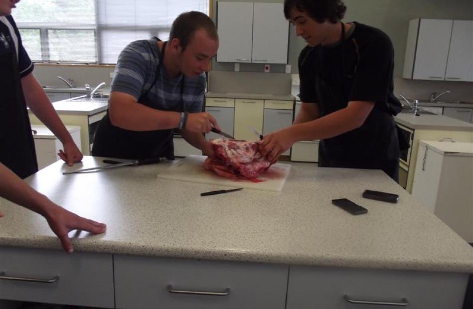 Pupils Tom Jenks (17, left)  and David Woodrow (17) butcher a wild pig's head. The classes are...