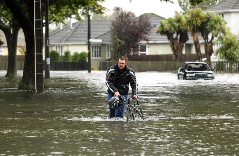 A cyclist wades through flooded streets in Edgeware, Christchurch. Photo by Getty
