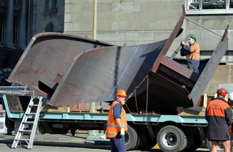 A crane lifts the first of two 4-tonne pieces, which is then lowered into place on the ground...