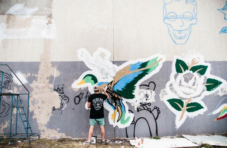Sydney-based street artist Alex Lehours works on an Authority Clothing mural on Beith St, in...