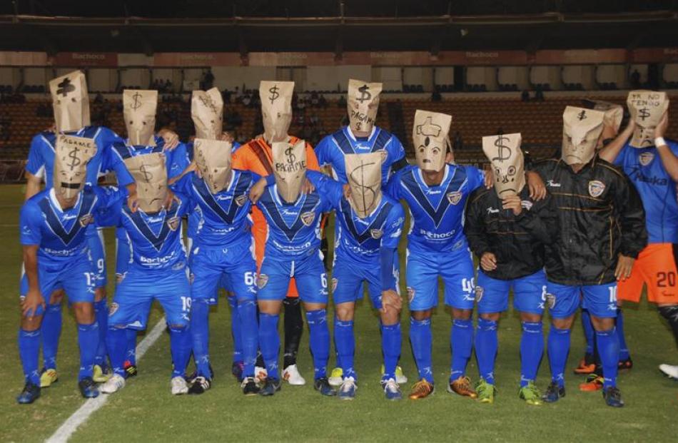 Players of the Mexican second division football team Celaya team pose with brown paper bags over...