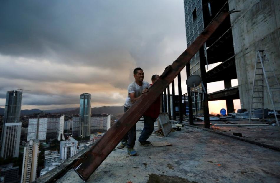 Men salvage metal on the 30th floor. REUTERS/Jorge Silva