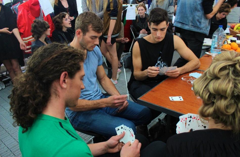 Models play cards to pass the time backstage.
