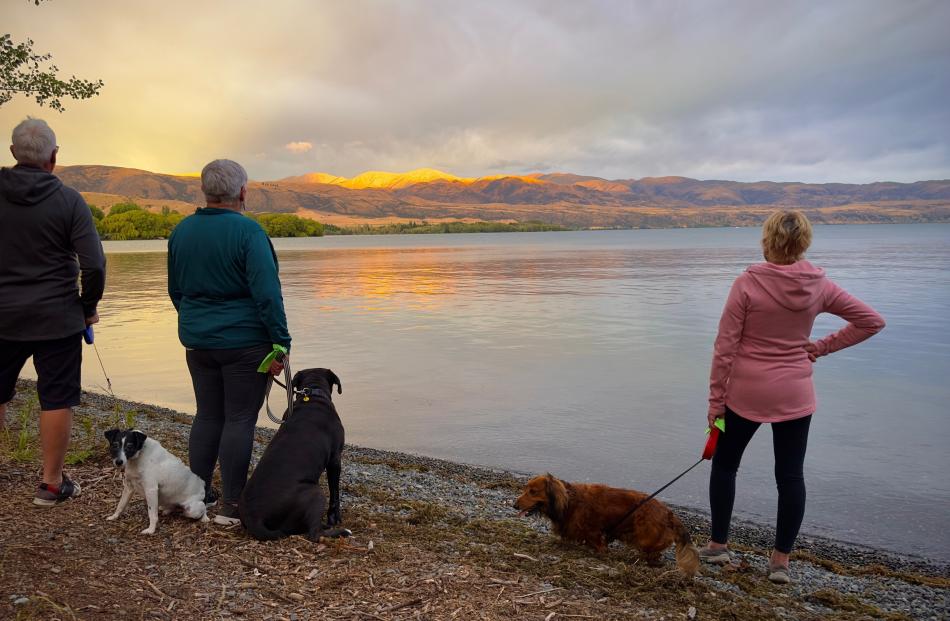 Serene scene ... Watching the sun set behind mountains at Lake Aviemore are (from left) David...