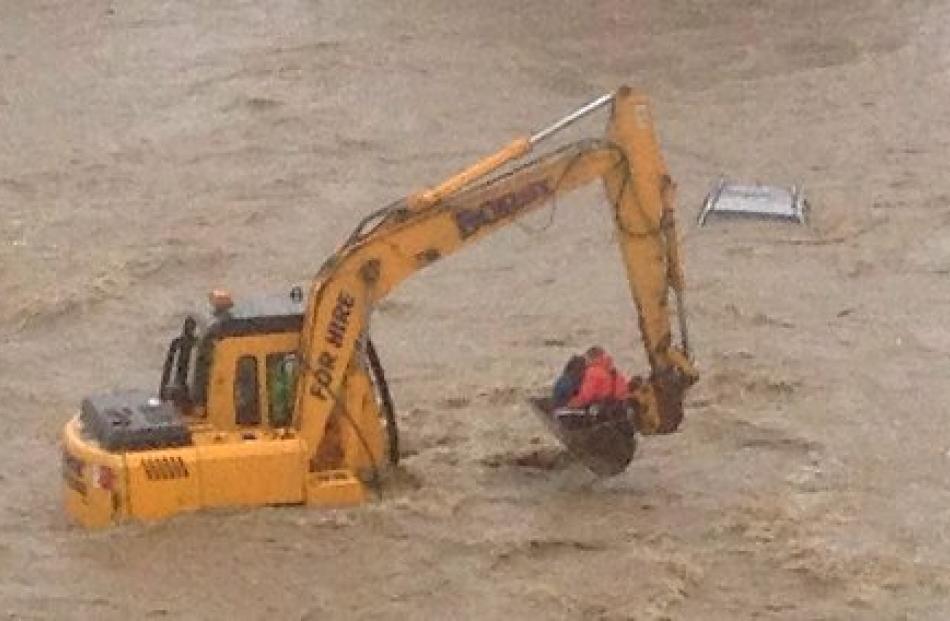 Sergeant Peter Muldrew, of Oamaru, and Mrs Davidson are taken to safety in the digger bucket.