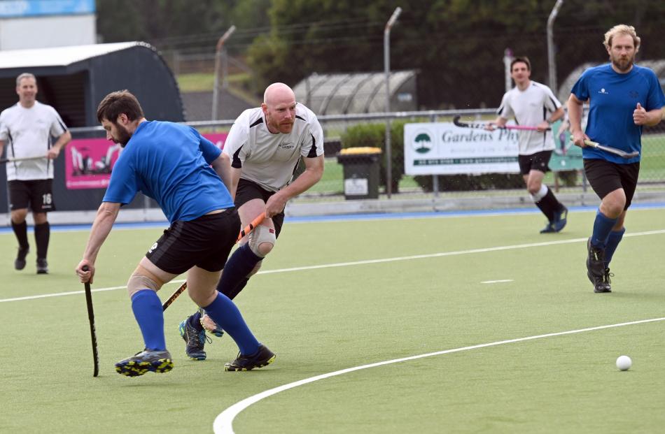 Southland Shags player Sam Moore (middle) clears the ball past Brendon Cook (left), of the...