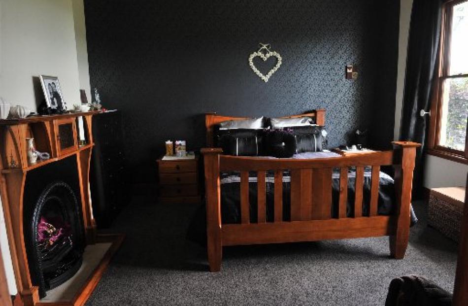 An original fireplace remains in the main bedroom. The dark wallpaper on the feature wall is a...