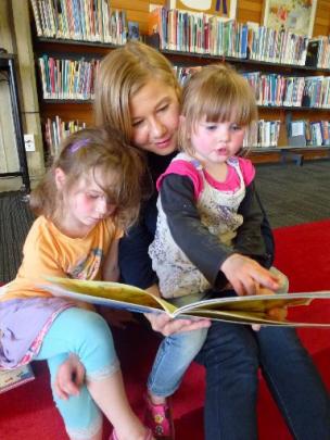 Miriam Geard reads to Charlotte Pomeroy (2) and sister Sophie (4).