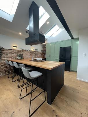 Skylights flood this new industrial-style kitchen with natural light. The induction cooktop is in...