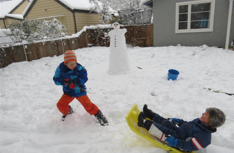 Austin Tyler (6) pulls his little brother Leo (4) on a sled in their front lawn in Arrowtown...