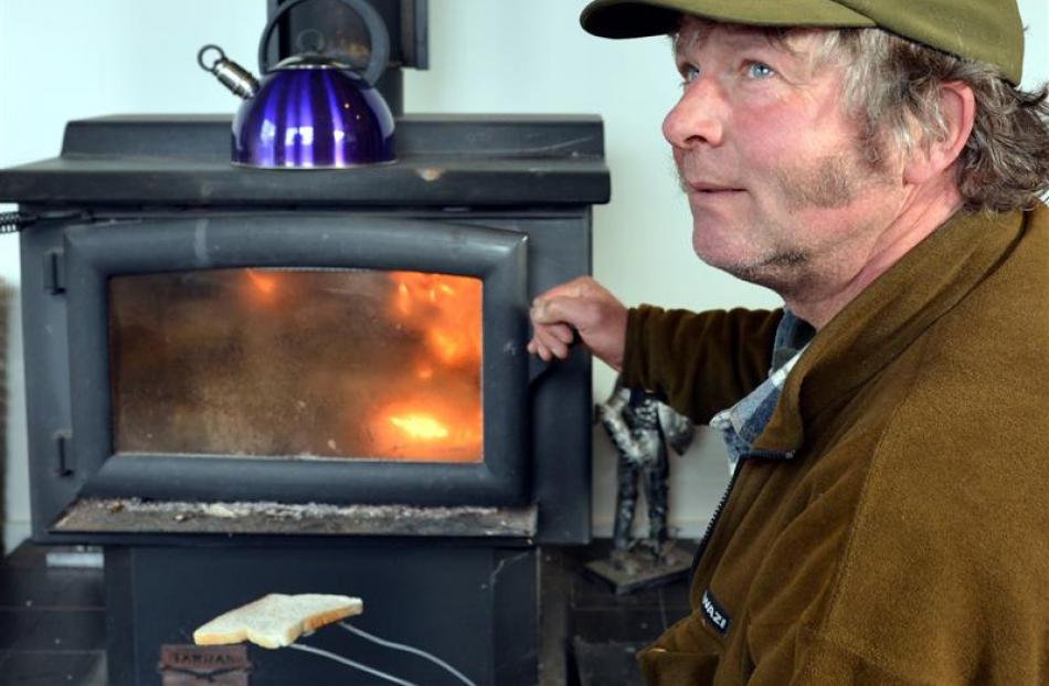 David McKay cooks toast on his log burner at his Cape Saunders home after strong winds knocked...