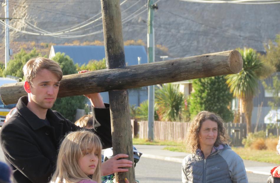 Dunedin siblings Will and Clara Stevens, 10, rest with a cross while listening to scripture...