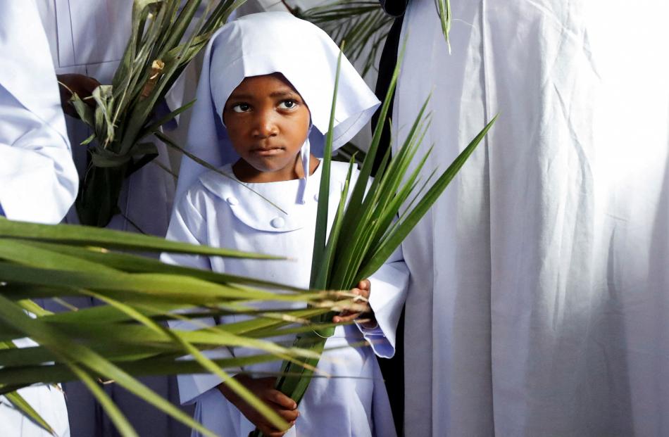 A child holds palm leaves as she attends a Palm Sunday mass at the St Mary’s Legio Maria of...