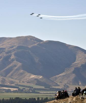 From their hillside perch, people watch the RNZAF Black Falcons fly in formation.