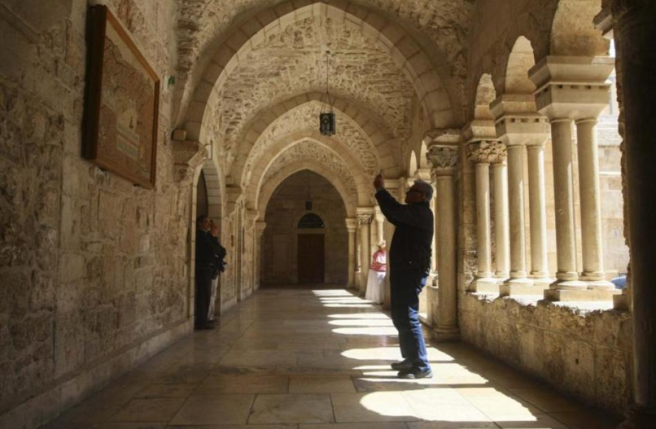 A tourist takes a picture with his mobile phone inside the Church of the Nativity in the West...