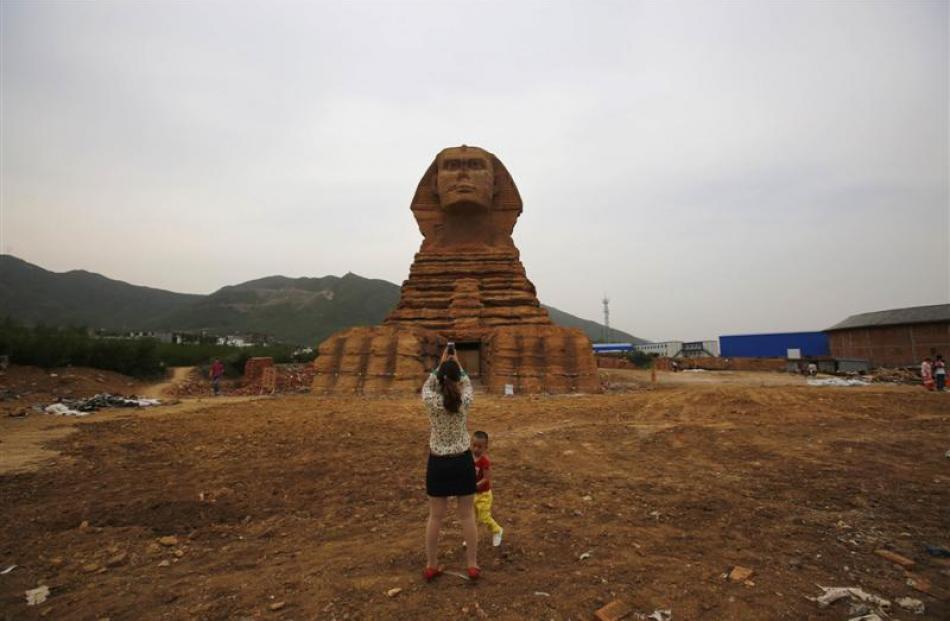 A woman takes pictures with her mobile phone as she and a boy visit a full-scale replica of the...