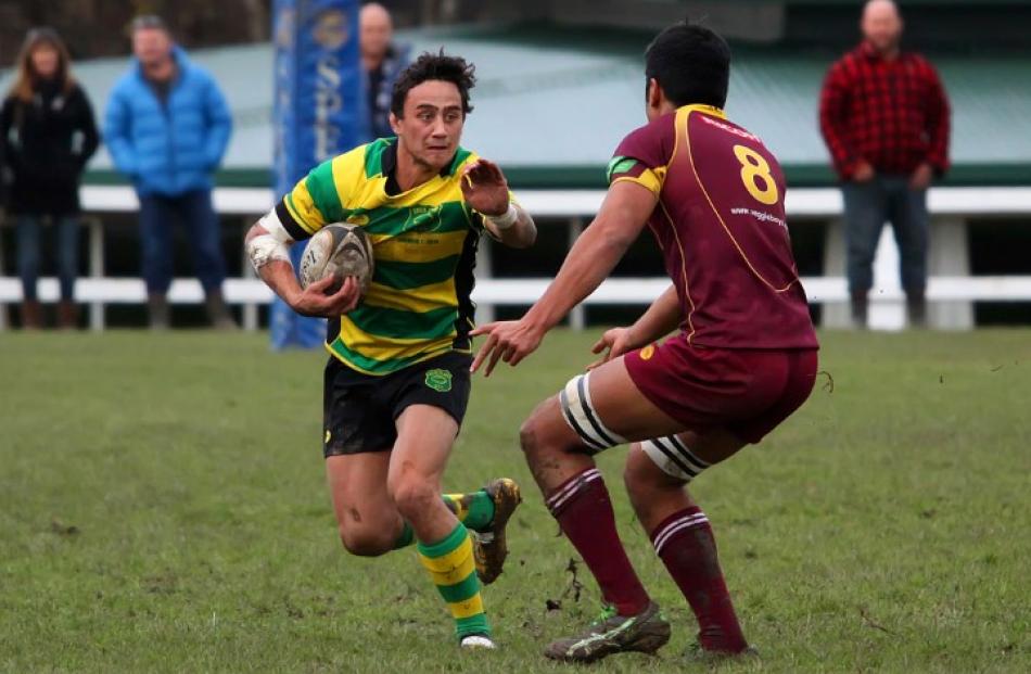 Green Island first five Sam Eriepa looks to beat the tackle of Alhambra Union No 8 Ben...