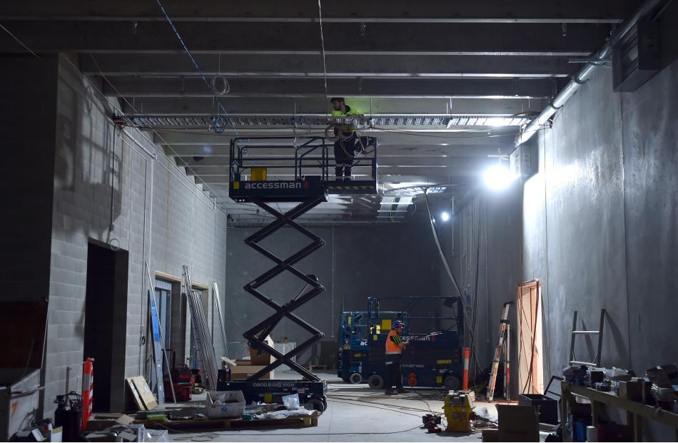 Contractors raise themselves towards the ceiling to work on the overhead lighting in a ground...