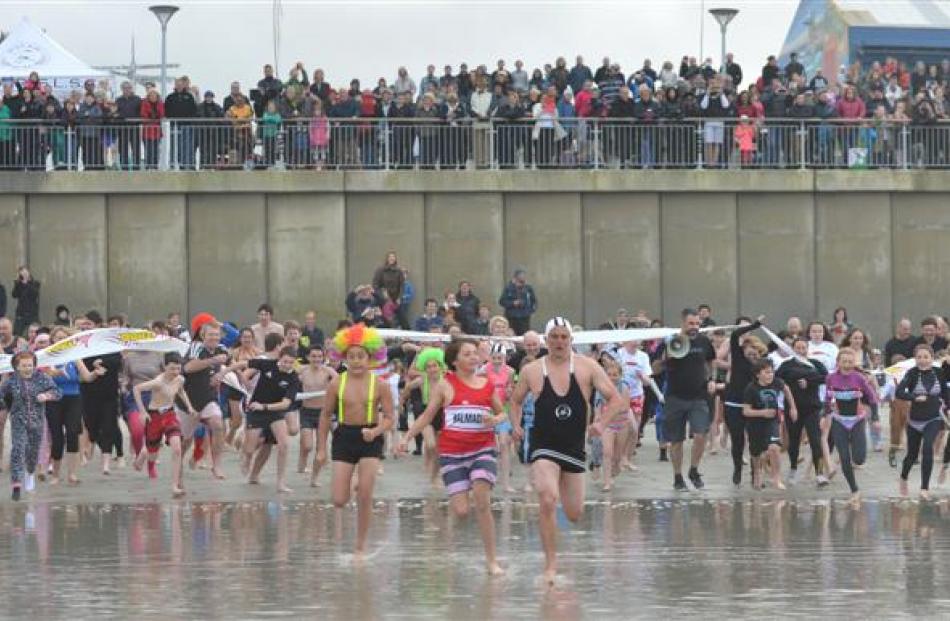 The crowd runs towards the water during the annual St Clair Surf Life Saving Club Polar Plunge at...