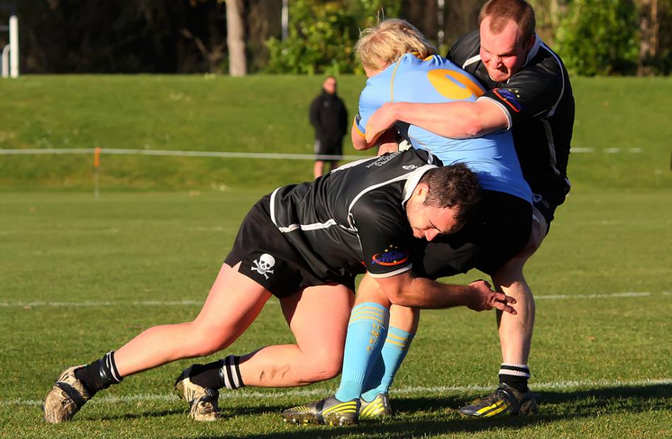 University A halfback Nick Annear is caught in the tackles of Pirates players Ben West and...