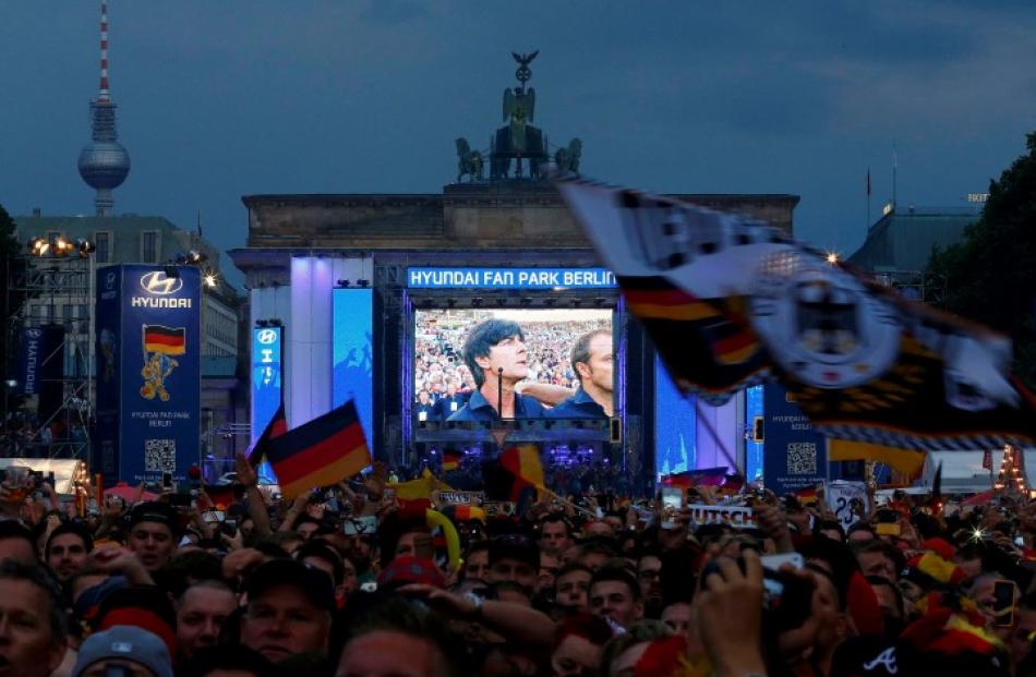 Team coach Joachim Loew is seen on a giant screen as fans wait for the match to start at a public...