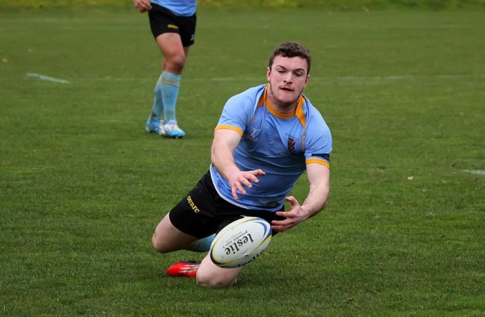 University A winger Gavin Stark dives to catch the ball from a kick.