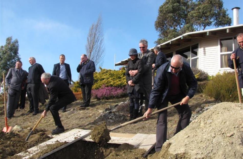 Mourners help fill the grave of Catholic priest Fr Brian Fenton  at his home in Wanaka yesterday....