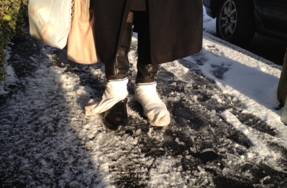 A pedestrian wears socks over shoes to aid traction in the slippery conditions on High St. Photo...