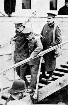 An injured soldier is helped down the gang plank.