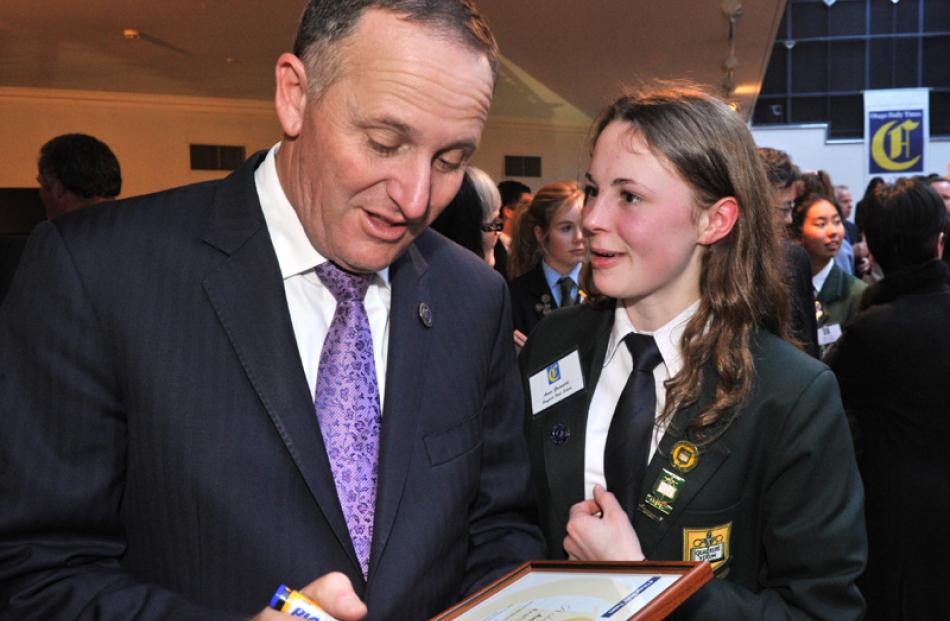 Anna Grimaldi of Bayfield High School talks with Prime Minister John Key as he signs her...