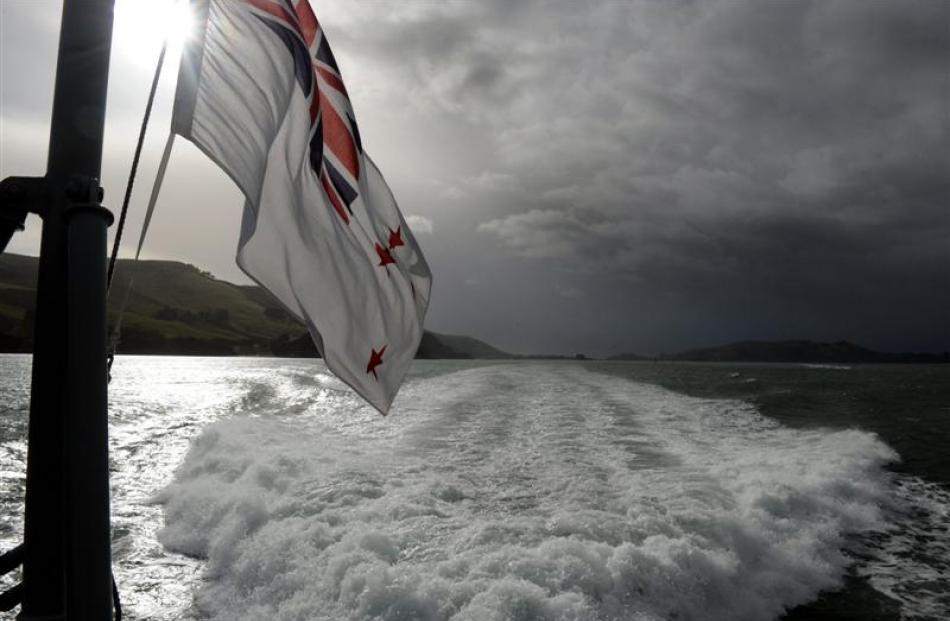 The ensign of the Royal New Zealand Navy flutters at the stern of HMNZS Rotoiti.