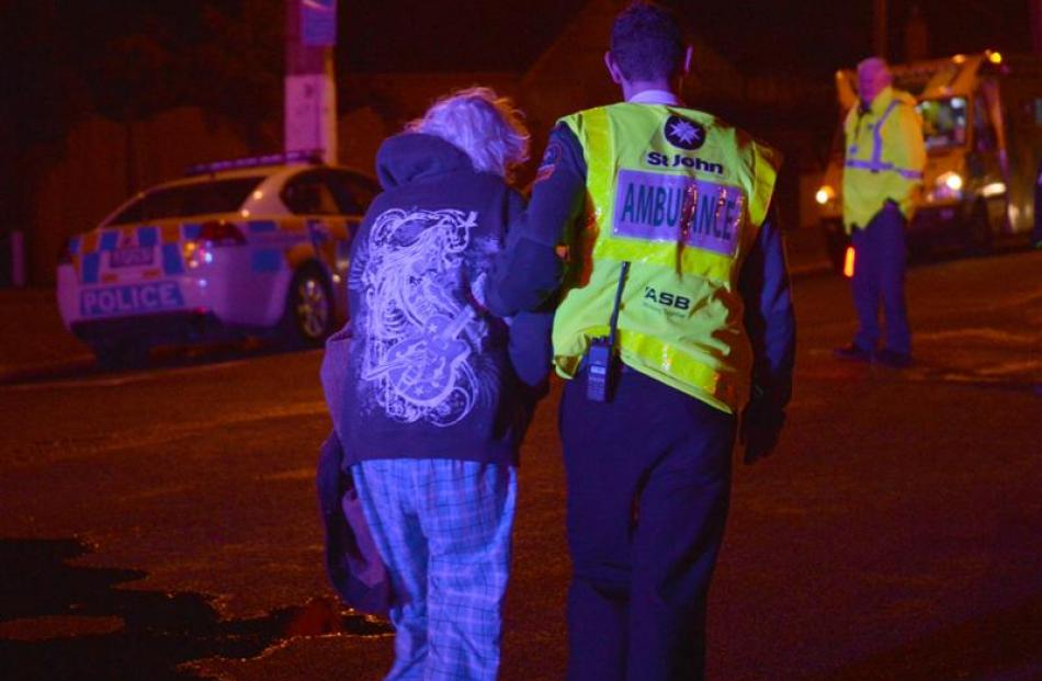One of the occupants of the house is helped to an ambulance.