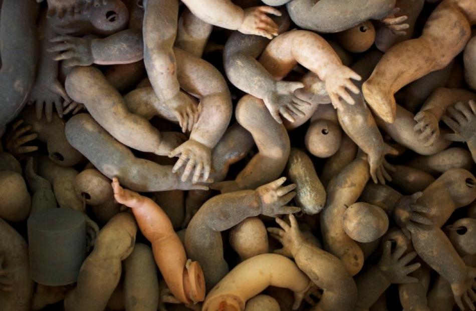 Spare doll limbs lie in a pile ready to be used in repairs.