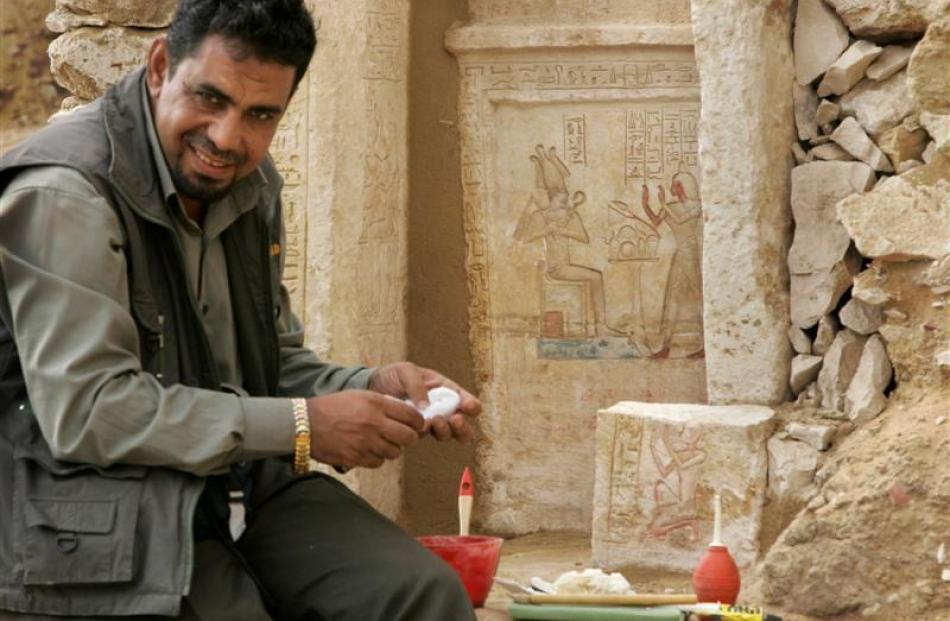 An archaeology worker cleans hieroglyphic details on a white limestone casing at the site of a...