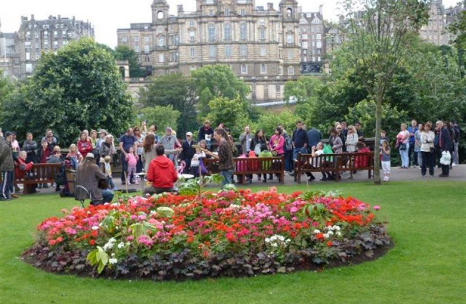 Musicians entertain passing crowds in the Princes Street Gardens. The backdrop building is the...