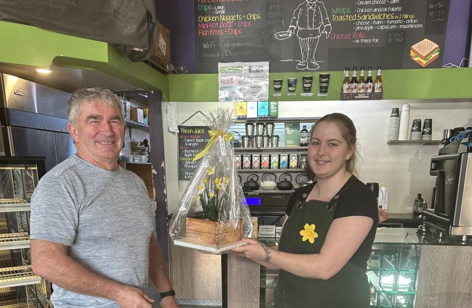 Ambience Cafe staff member Devon Morris-Brown presents the Daffodil Day cake raffle prize he won...