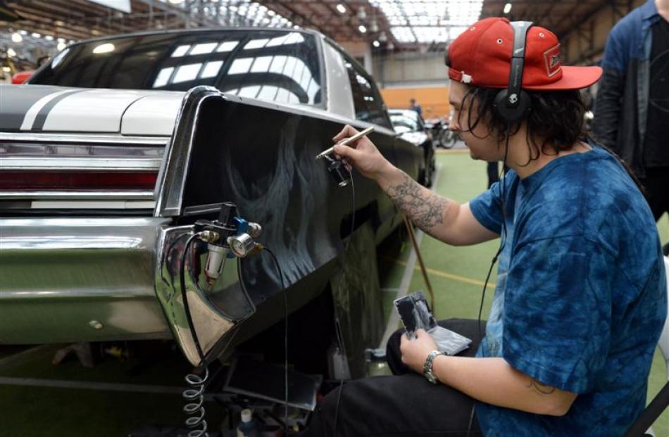 Ben Waldron (24) spray-paints a skull on to the right quarter panel of a car.