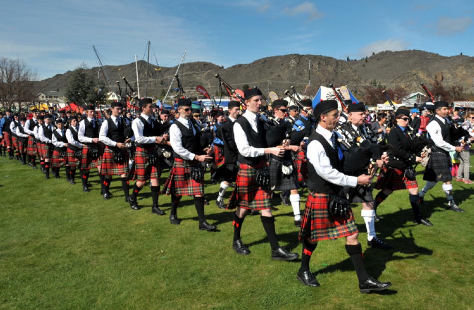 Combined pipe band members march through Pioneer Park.