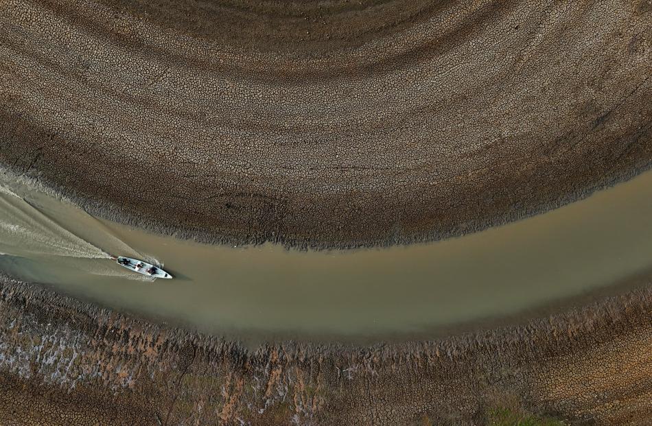 A drone view shows fishermen pushing an aluminium canoe to try to go fishing, in the middle of...