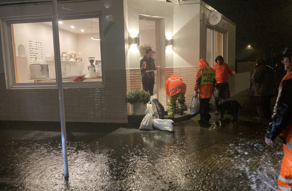 People fill sandbags at the Junction Cafe, on the corner of Hargest Crescent and Richardson St,...